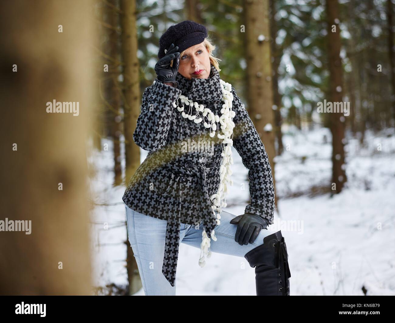 Fashionable mature adult woman wearing winter clothes, rural scene, forest on background. South Finland in January. Stock Photo