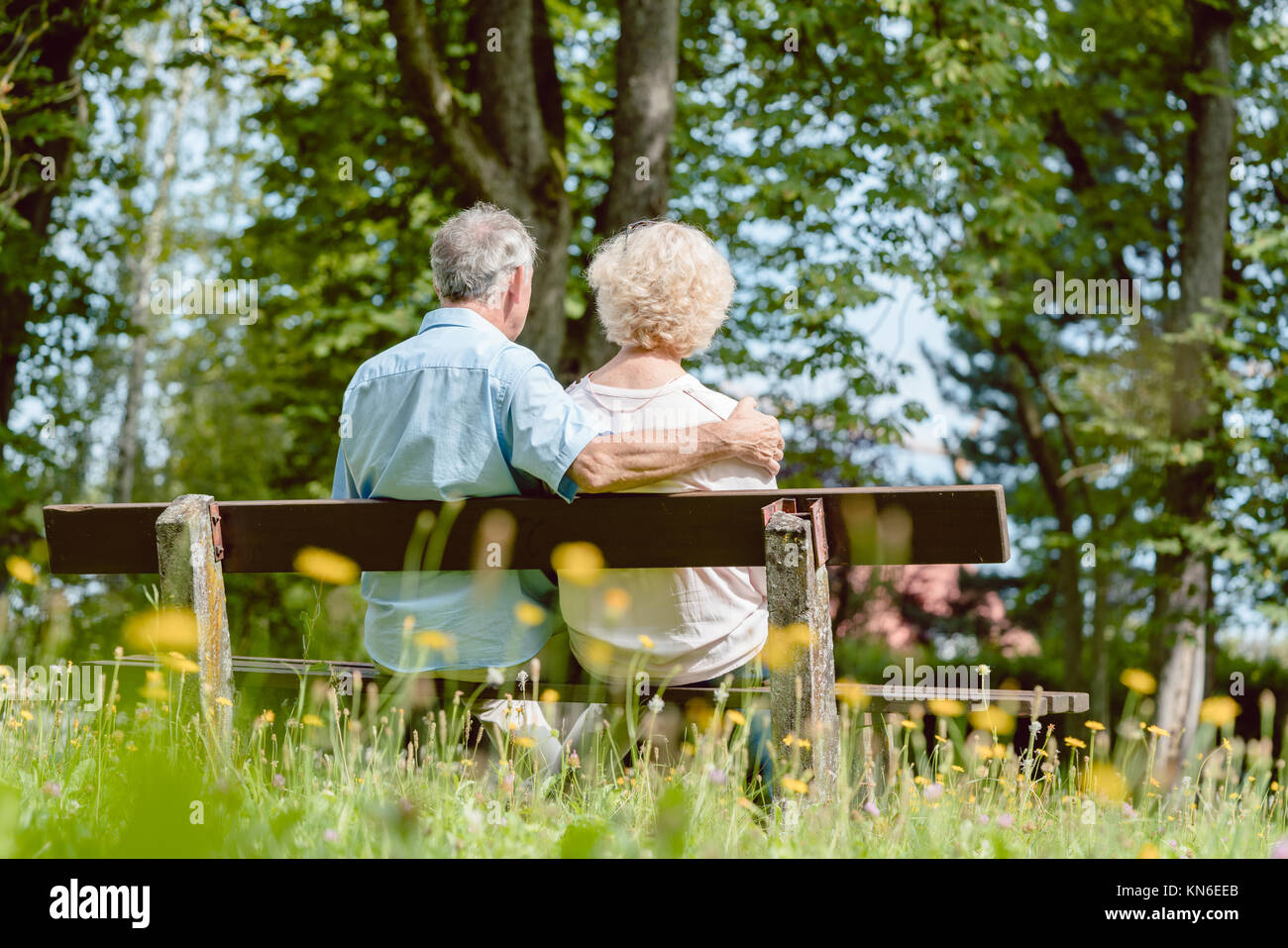 Romantic elderly couple sitting together on a bench in a tranqui Stock Photo