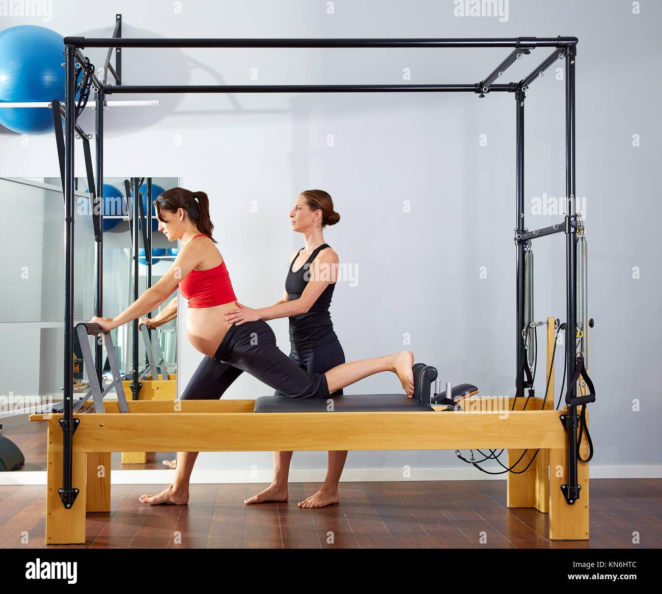pregnant woman pilates reformer cadillac exercise workout with personal