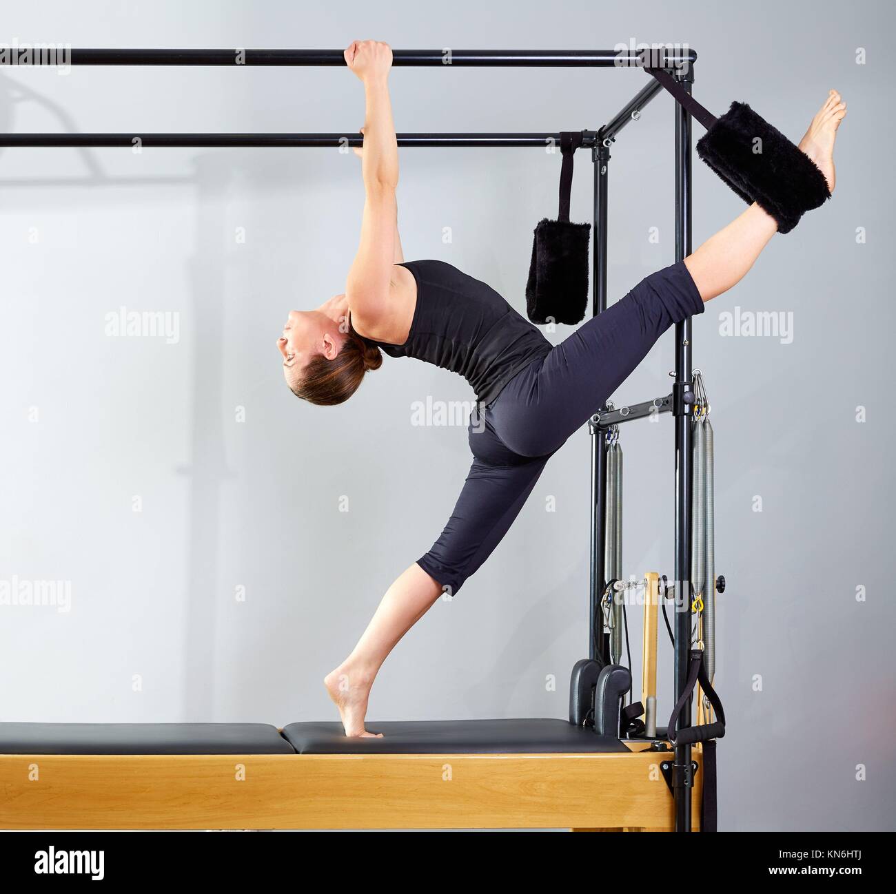 Pilates woman in cadillac split legs stretch exercise at gym Stock