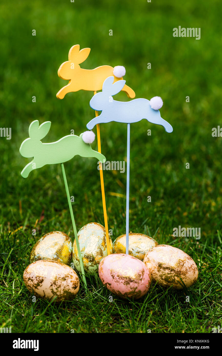 Wooden Bunnies and Golden Eggs as Symbols of Easter, on Dark Green