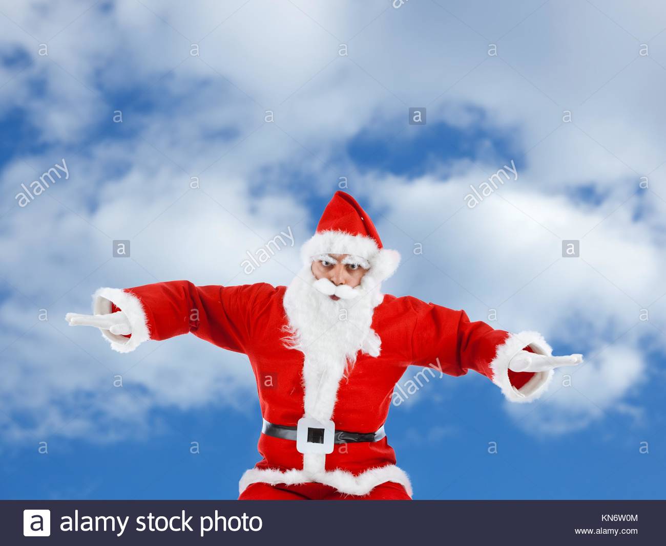 Santa Claus mimics a plane while flying in the sky Stock Image