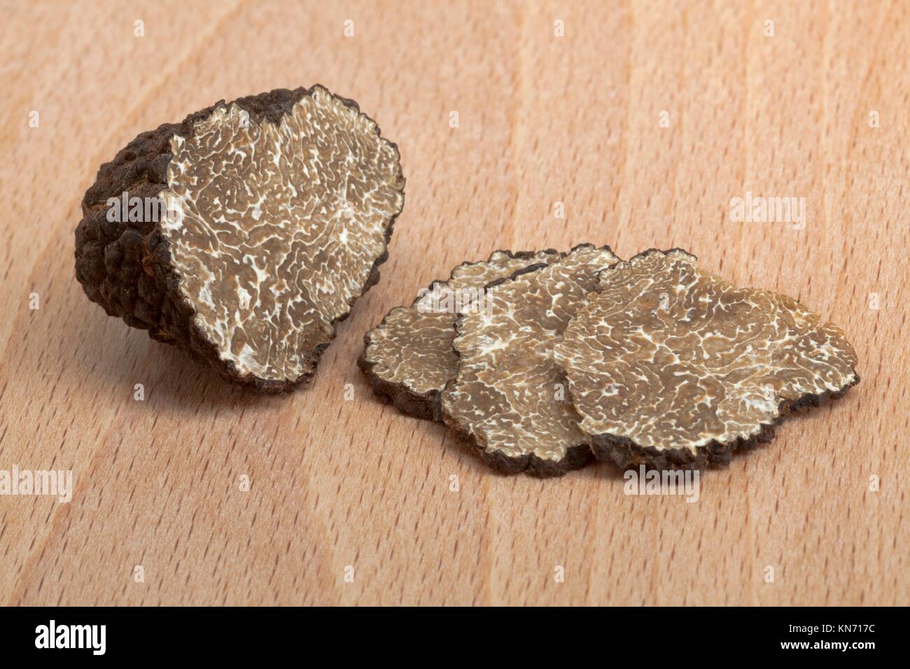 Fresh black truffle and slices on wood. Stock Photo