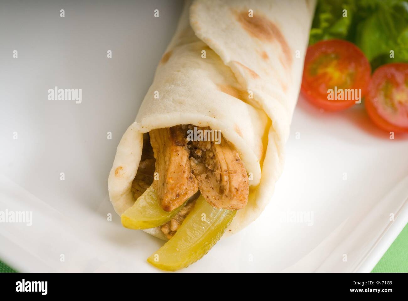 pita bread chicken roll with pickles cucumbers on a plate with pachino