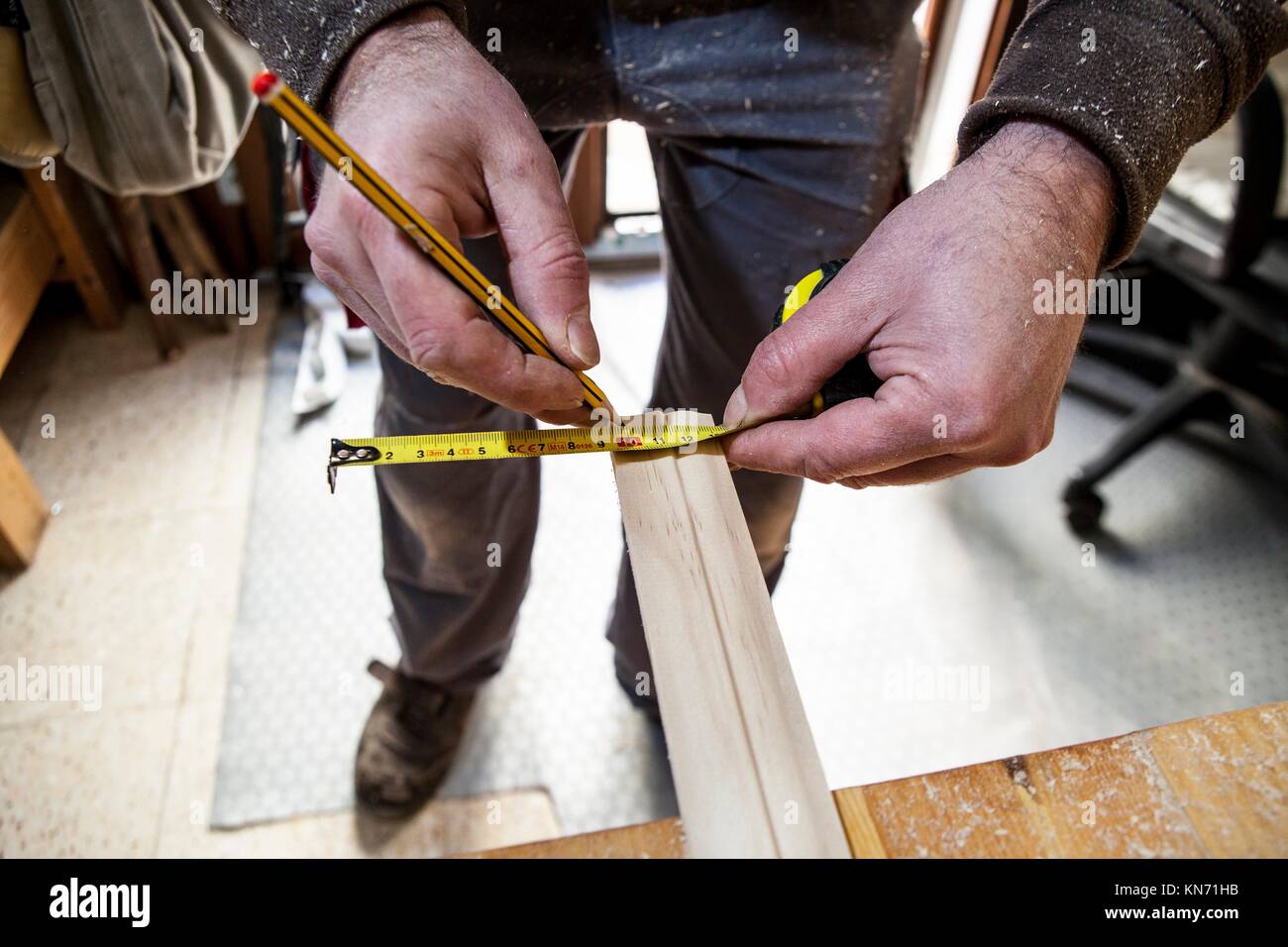 Carpenter working with doorjambs. He is measuring wood and marking with pencil. Stock Photo