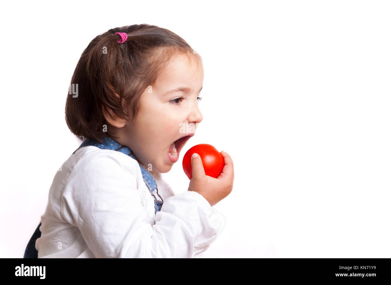 Portrait of happy girl holding a tomato. Isolated over white background. Stock Photo