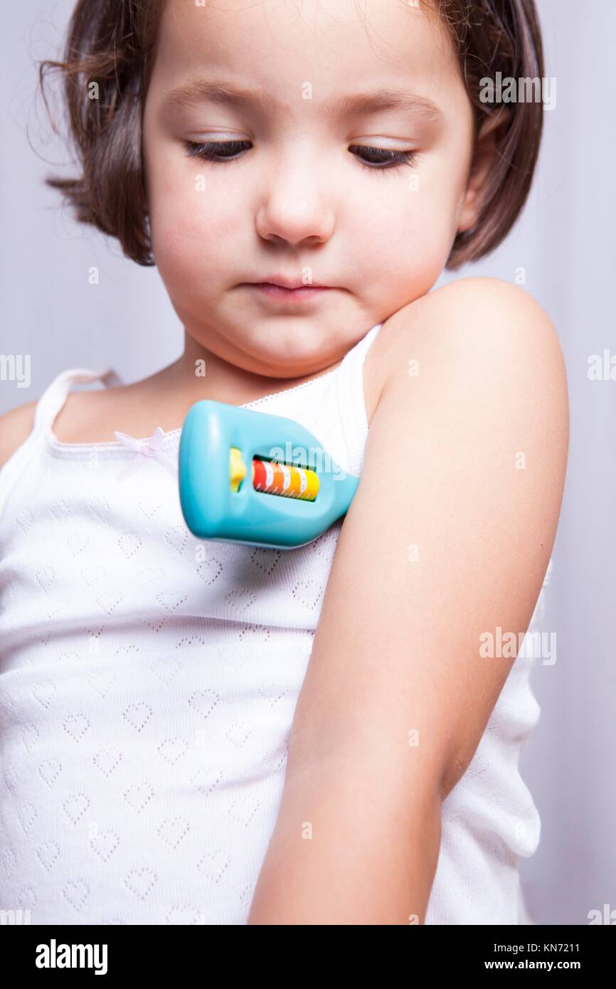 Cute little girl playing doctor with toy thermometer. Isolated over white background. Stock Photo