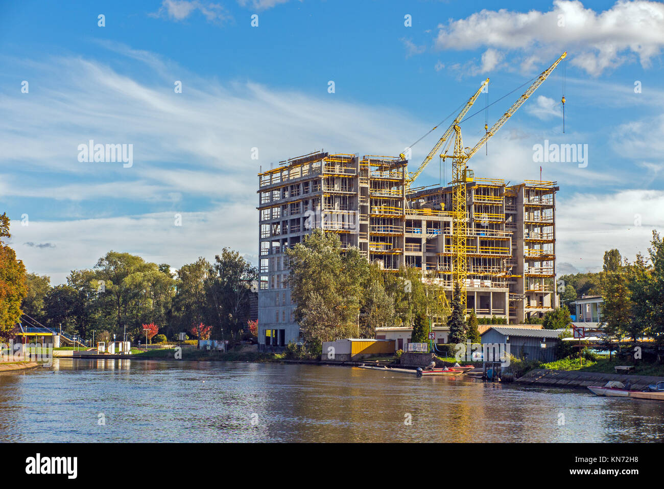 Building new homes on the banks of the river Brda in the Polish city of Bydgoszcz Poland using a large yellow crane Stock Photo
