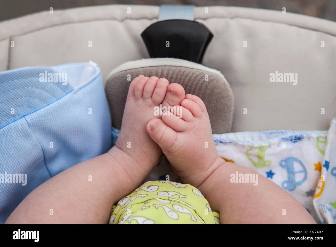 Chubby feet of a newborn baby boy in stroller while on a walk outside in the street. Stock Photo