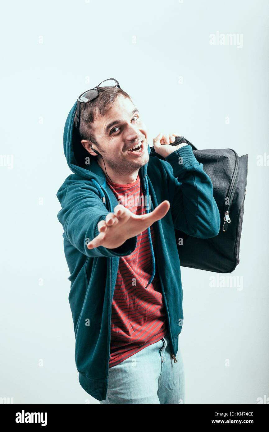 Ecstatic man in hoodie traveling with luggage. Stock Photo