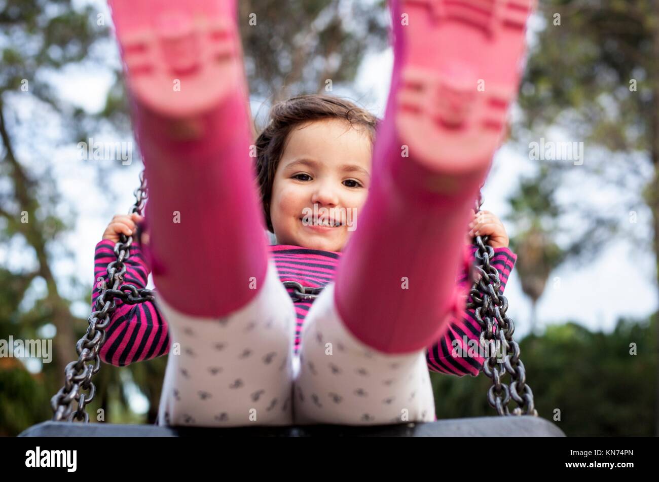 Happy three year old girl having fun on a swing. Selective focus. Stock Photo