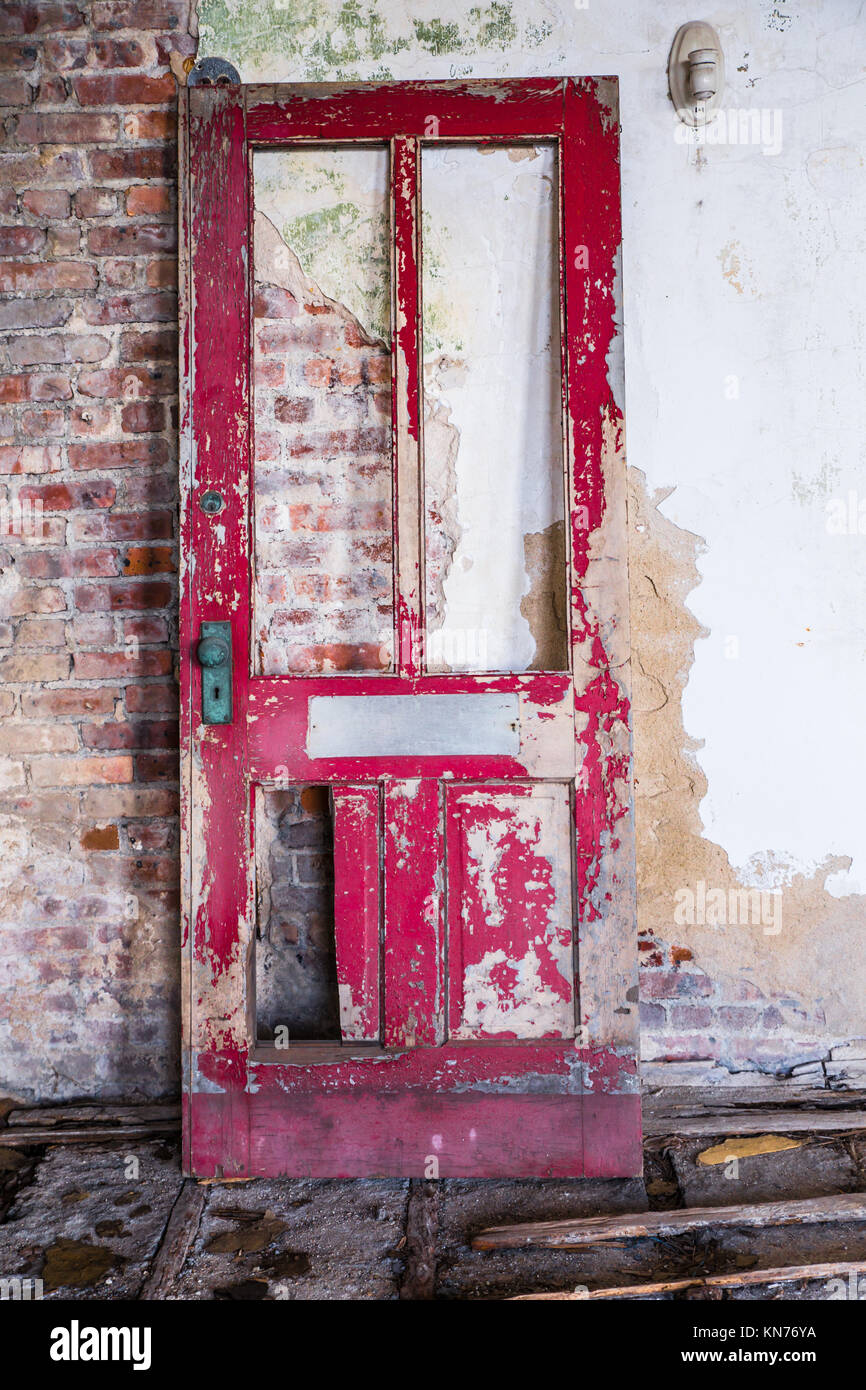 Broken wooden door against brick wall in abandoned building Stock Photo