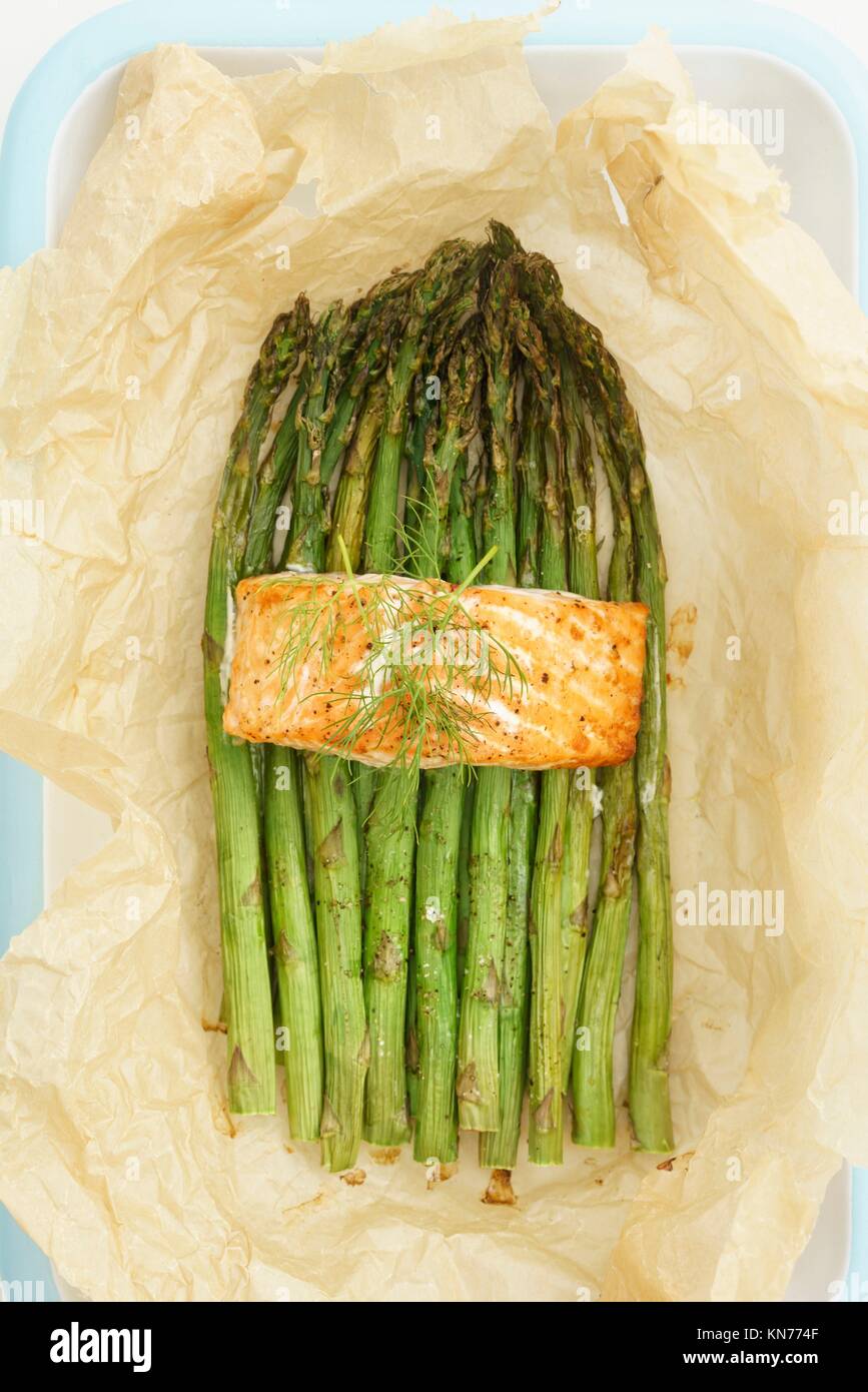 Baked green asparagus with salmon with parchment paper in a casserole. Stock Photo