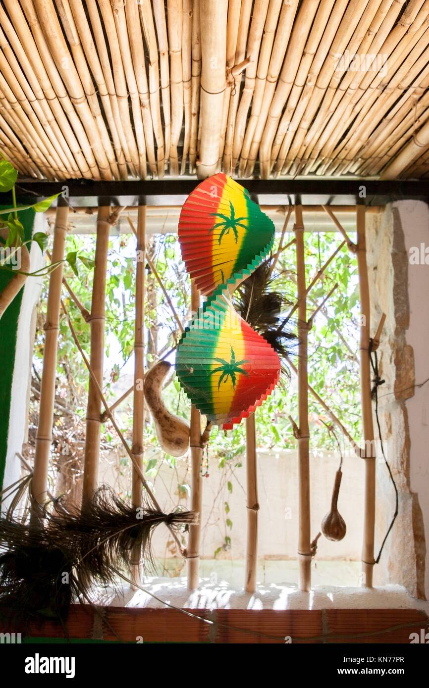 Hanging wooden spiral decorative craft with reggae color over open window of a tropical hut. Stock Photo