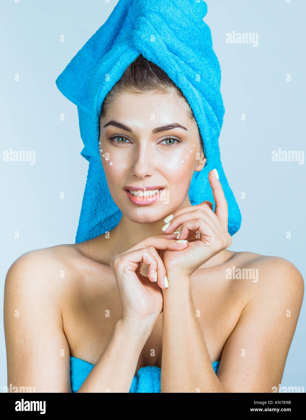 Beautiful woman with towel on head applying creme after shower Stock