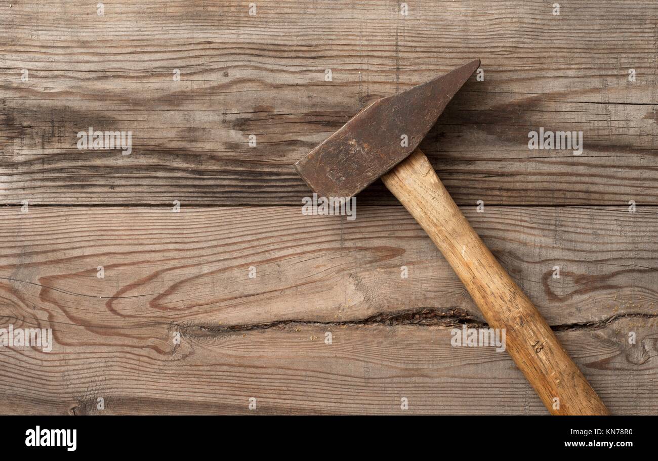 Vintage hammer lying on wooden surface of workbench. Conceptual image of home improvement, DIY and carpentry. Stock Photo