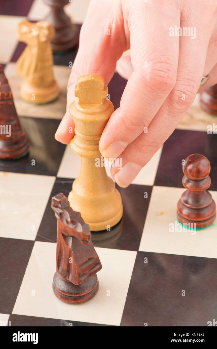 A skilled hand deftly slides a chess piece marked Chess across