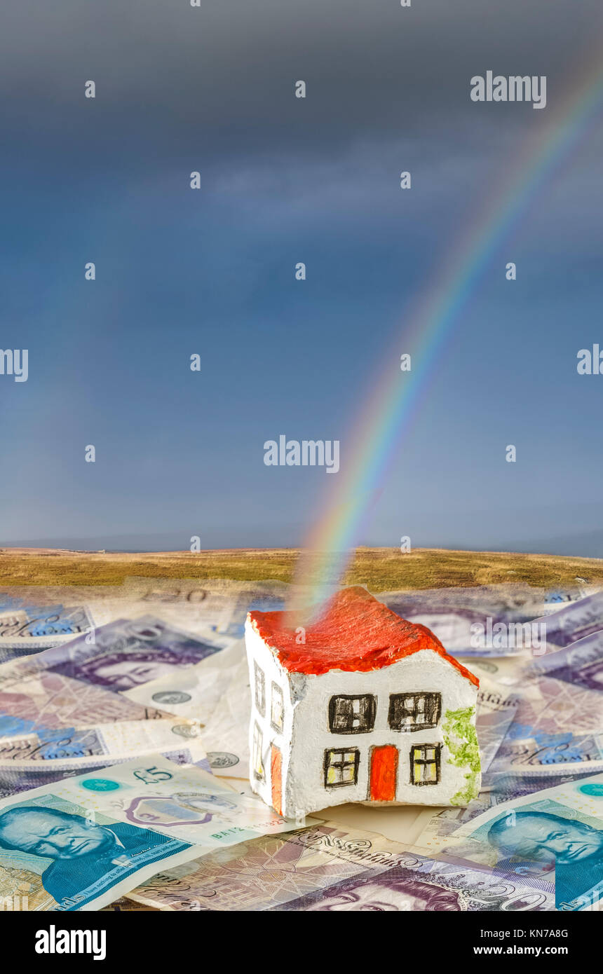 Hand painted stone house sitting on British currency notes with a genuine rainbow ending at the house suggesting savings on stamp duty Stock Photo