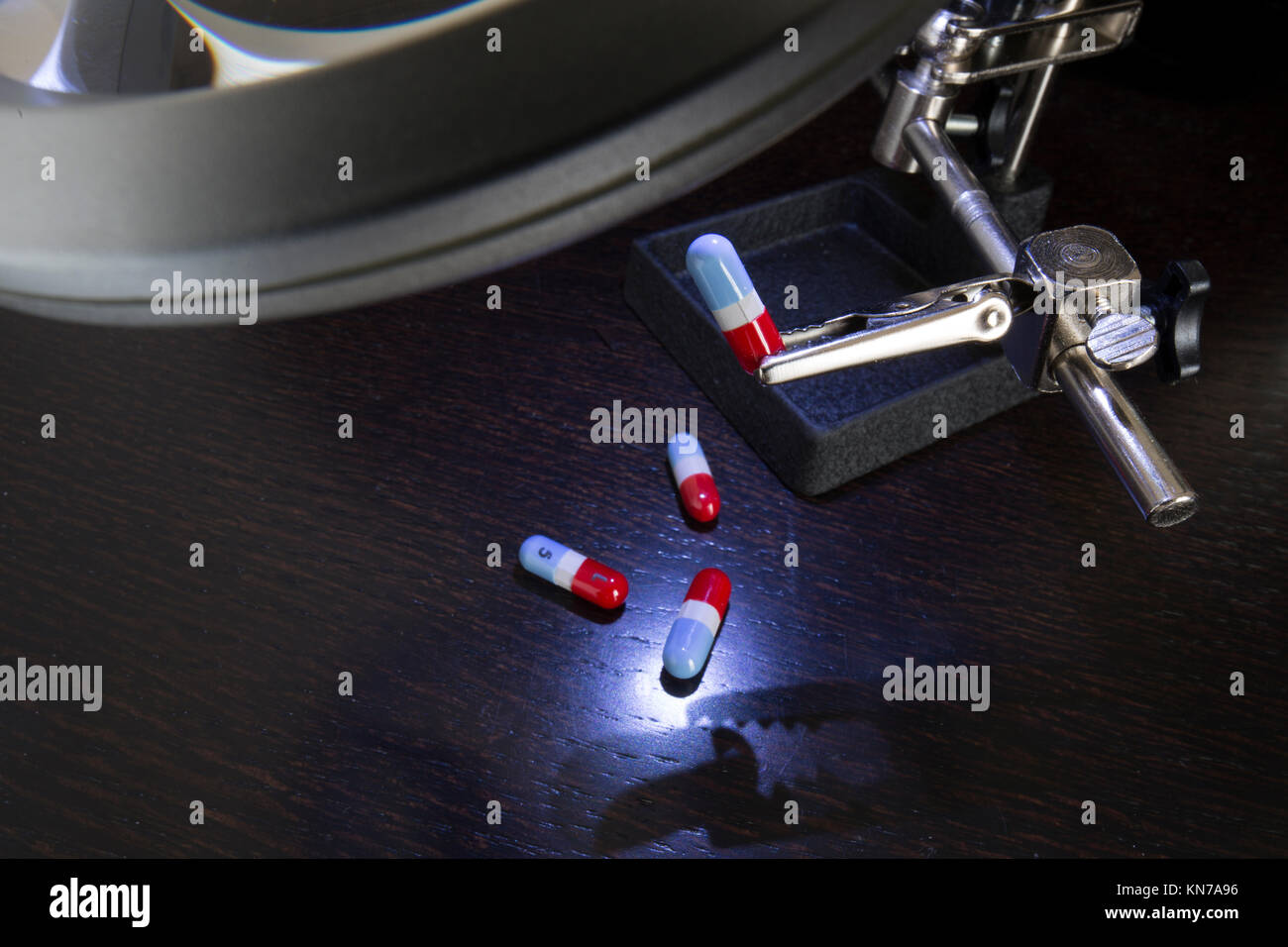 Precision magnifying glass with led inspection light inspecting medication capsules Stock Photo
