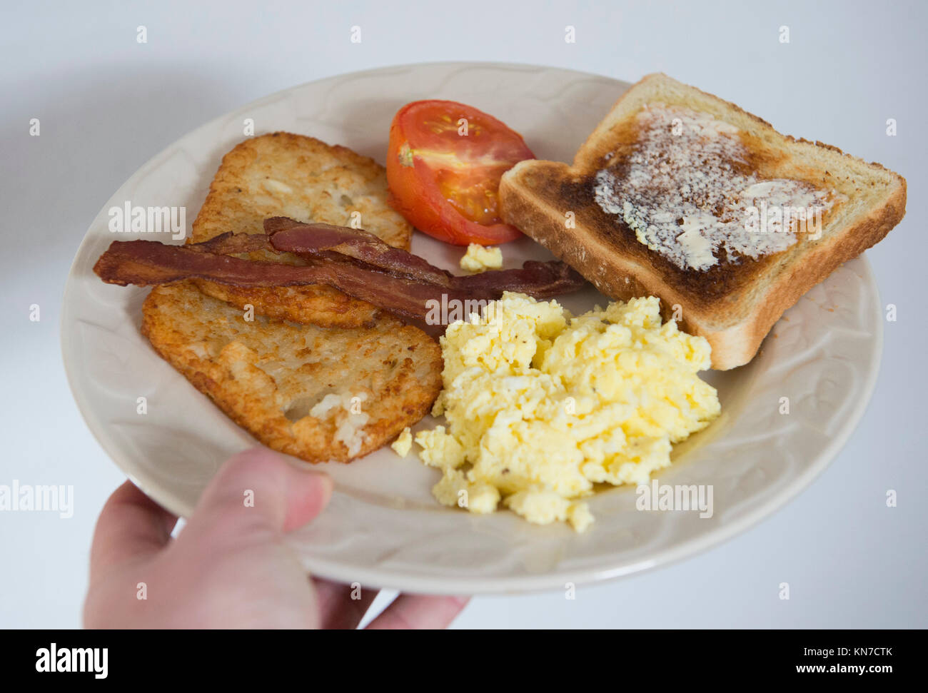 A Breakfast Consisting Of Bacon Hash Browns Tomato Toast And Scrambled Eggs Is Shown On A Plate Stock Photo Alamy