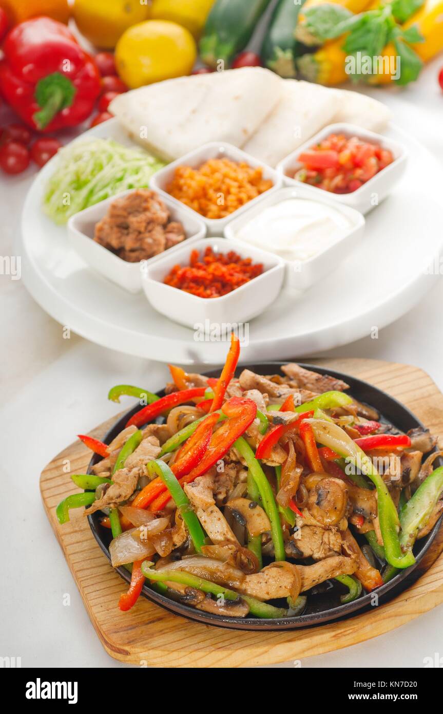 original fajita sizzling smoking hot served on iron plate and fresh vegetables on background