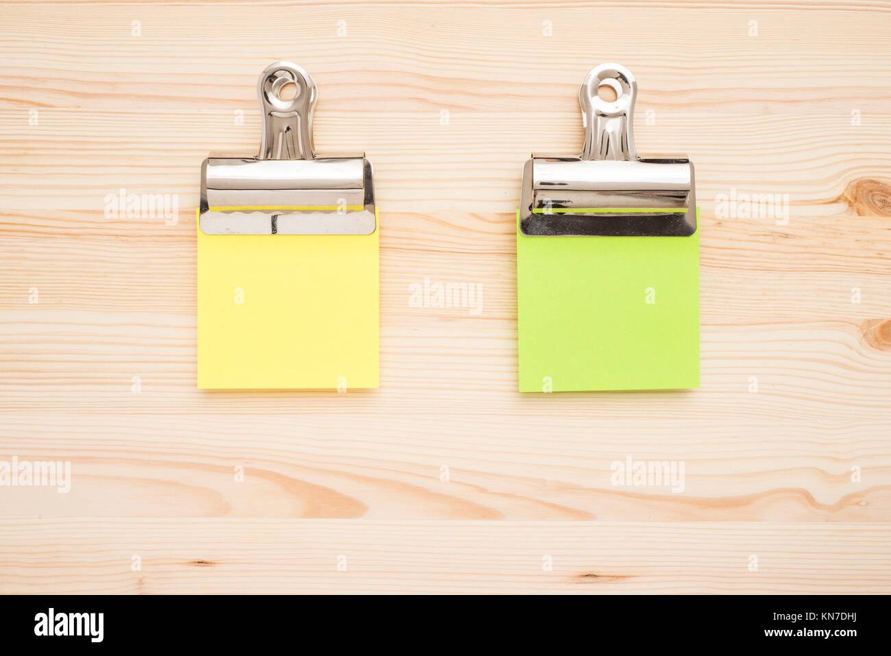 Two empty sticky notes on wooden table. Office desktop background with