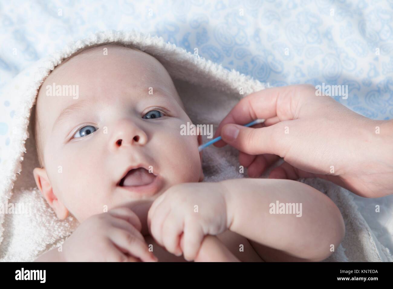 Mother cleaning ear with cotton swab to her baby boy. Selective focus