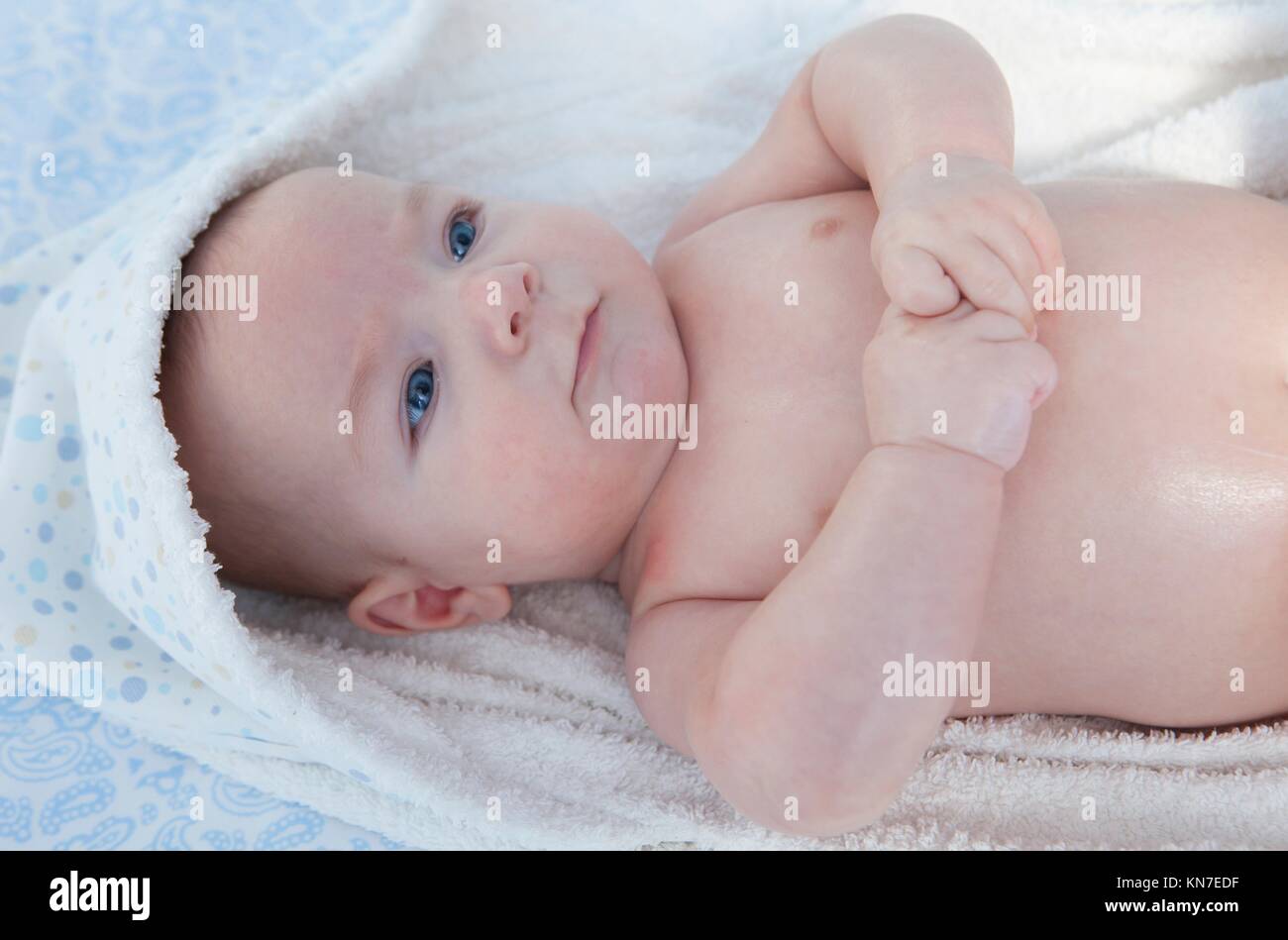 Cute three month baby wrapped bath towel after bath in bed at home