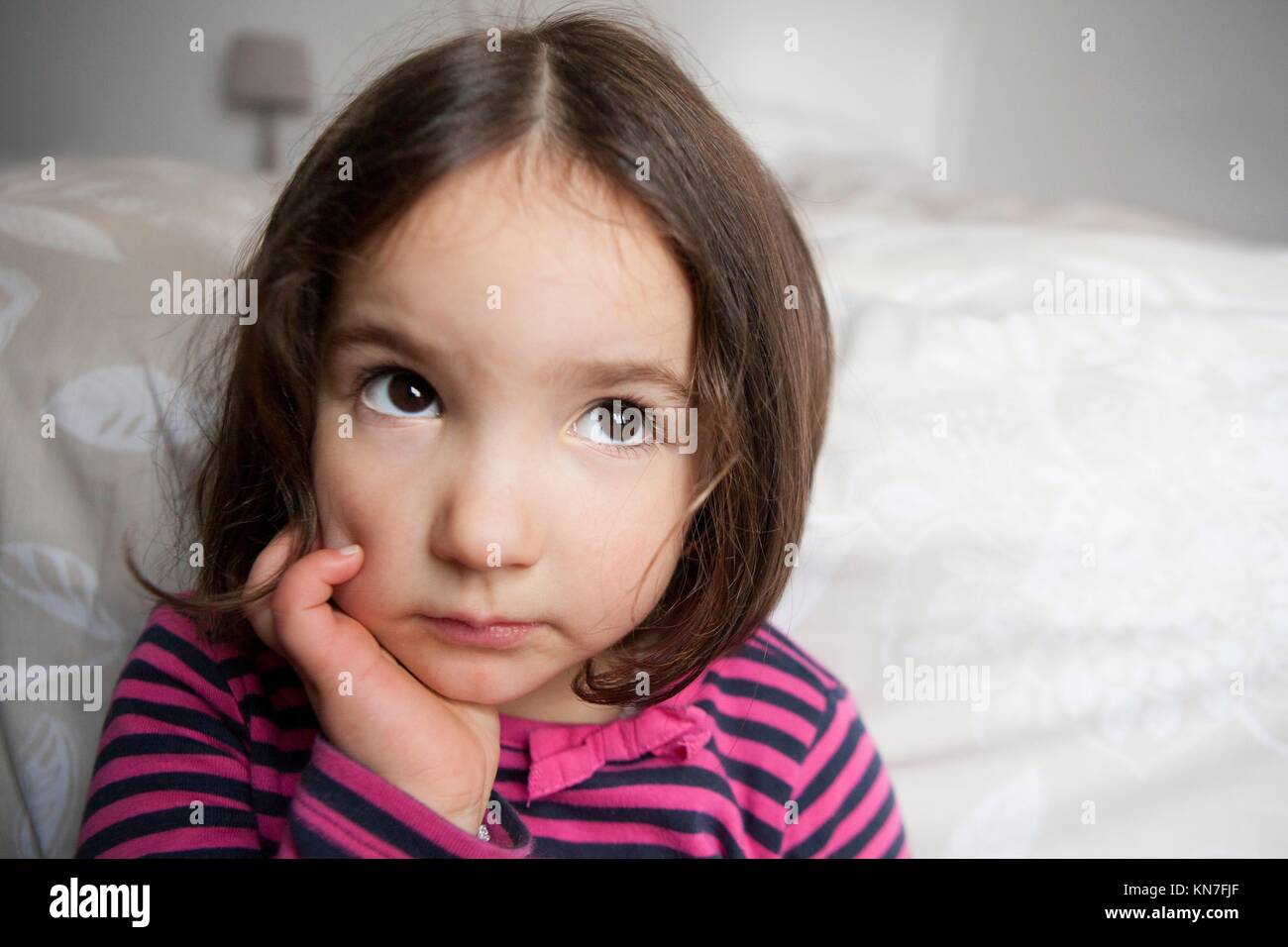 Hopeful three years old little girl. Indoors portrait. Stock Photo