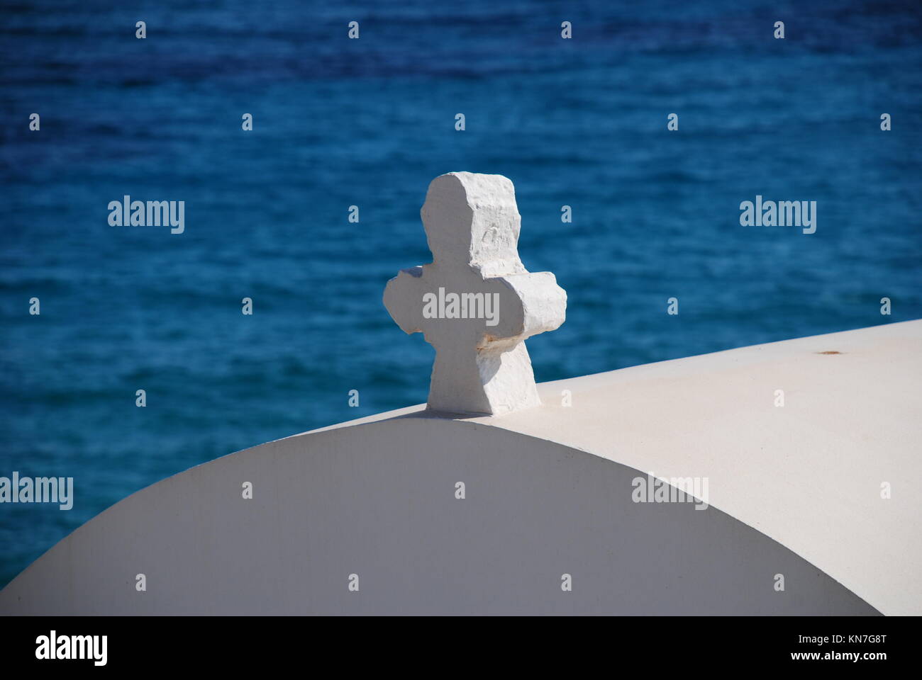 The cross on the roof of a small seafront chapel by Pondamos beach at Emborio on the Greek island of Halki. Stock Photo