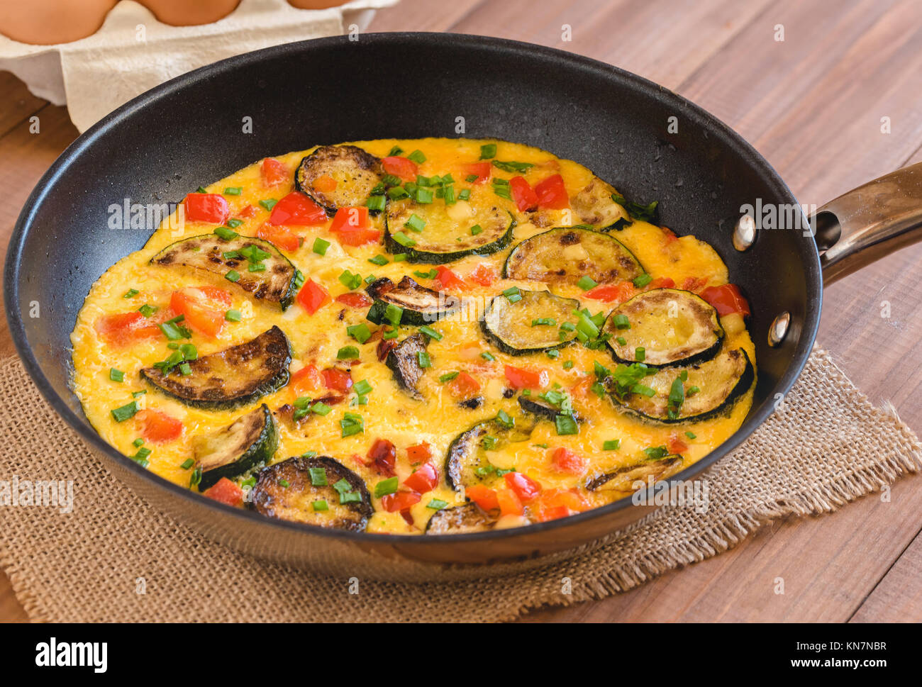 Omelette with zucchini, red paprika and chives. Frittata in frying pan