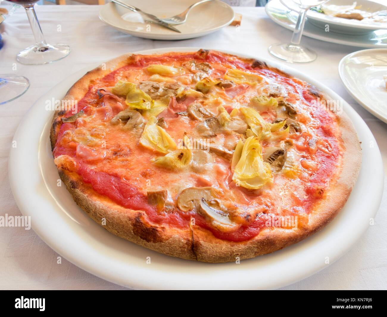 artichokes, mushrooms and tomato pizza on white circular plate between