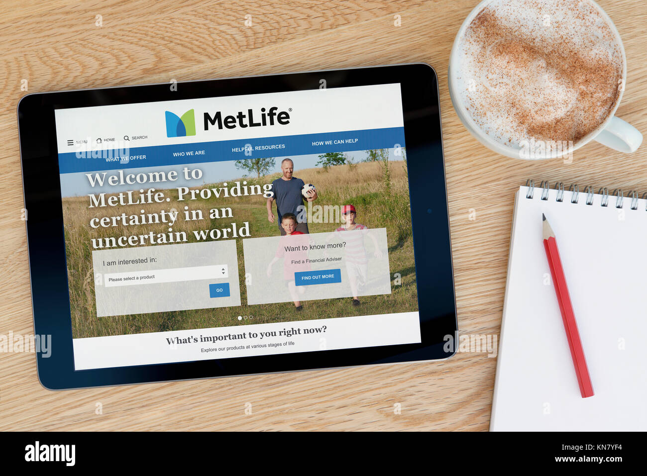 The MetLife website on an iPad tablet device which rests on a wooden table beside a notepad and pencil and a cup of coffee (Editorial only) Stock Photo