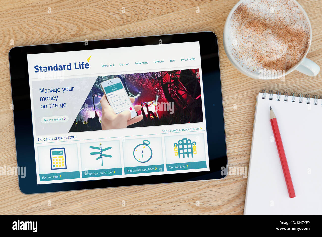 The Standard Life website on an iPad tablet device which rests on a wooden table beside a notepad and pencil and a cup of coffee (Editorial only) Stock Photo