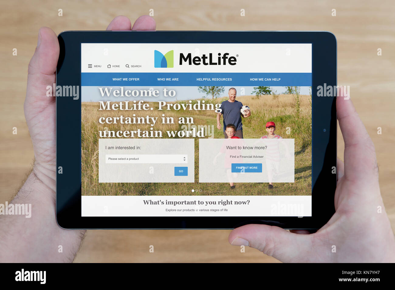 A man looks at the MetLife website on his iPad tablet device, shot against a wooden table top background (Editorial use only) Stock Photo