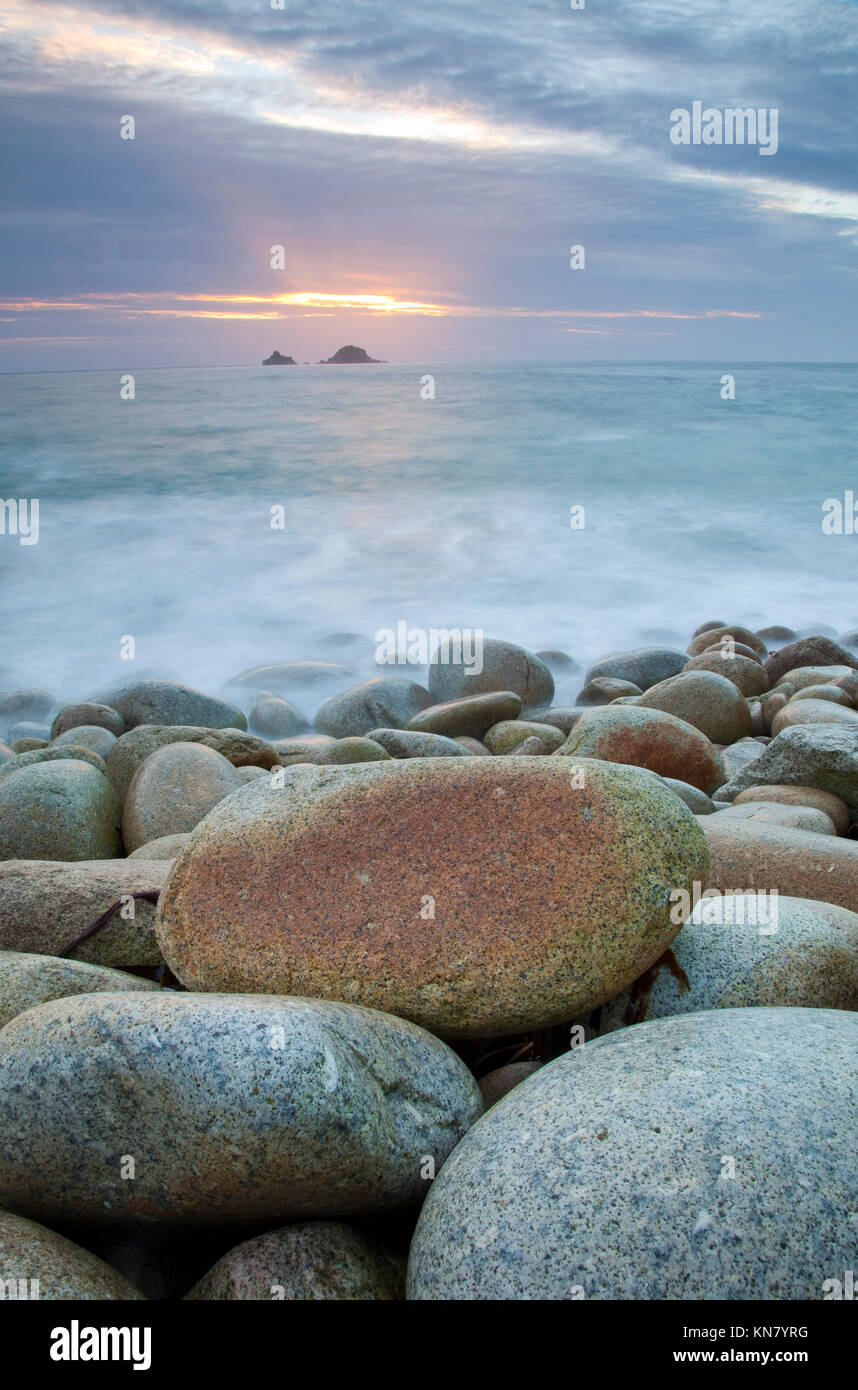 West Cornwall ocean at sunset with moving water rolling over large beach pebbles Stock Photo