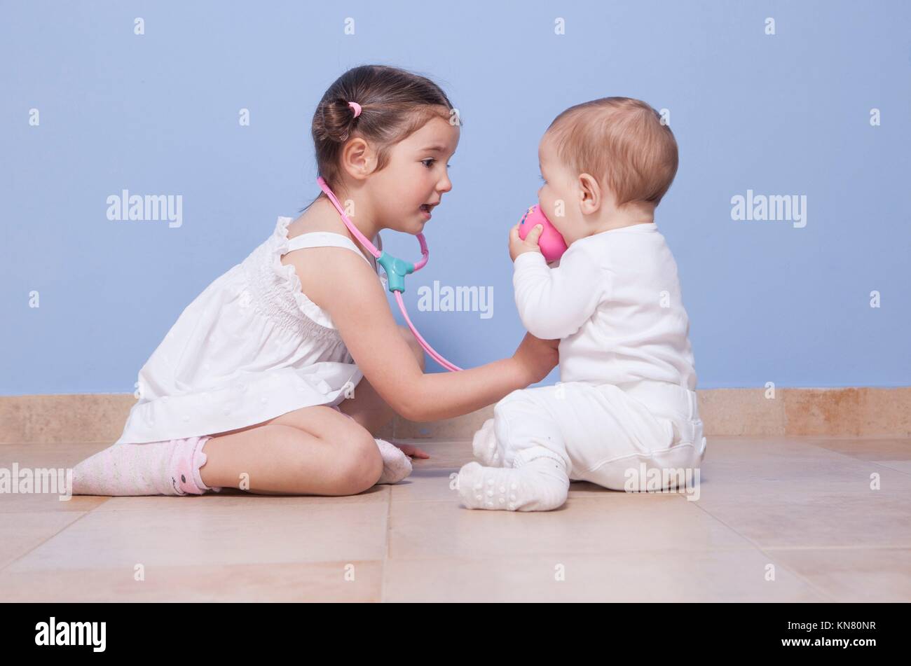 Baby brother and toddler sister playing doctor with stethoscope. Stock Photo