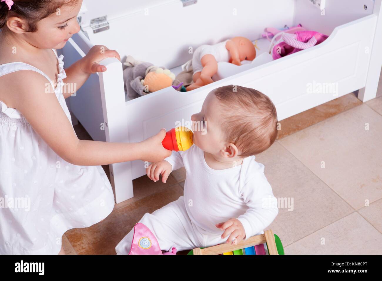 Baby boy playing with his sister at toys room. They are singing with a toy microphone. Stock Photo