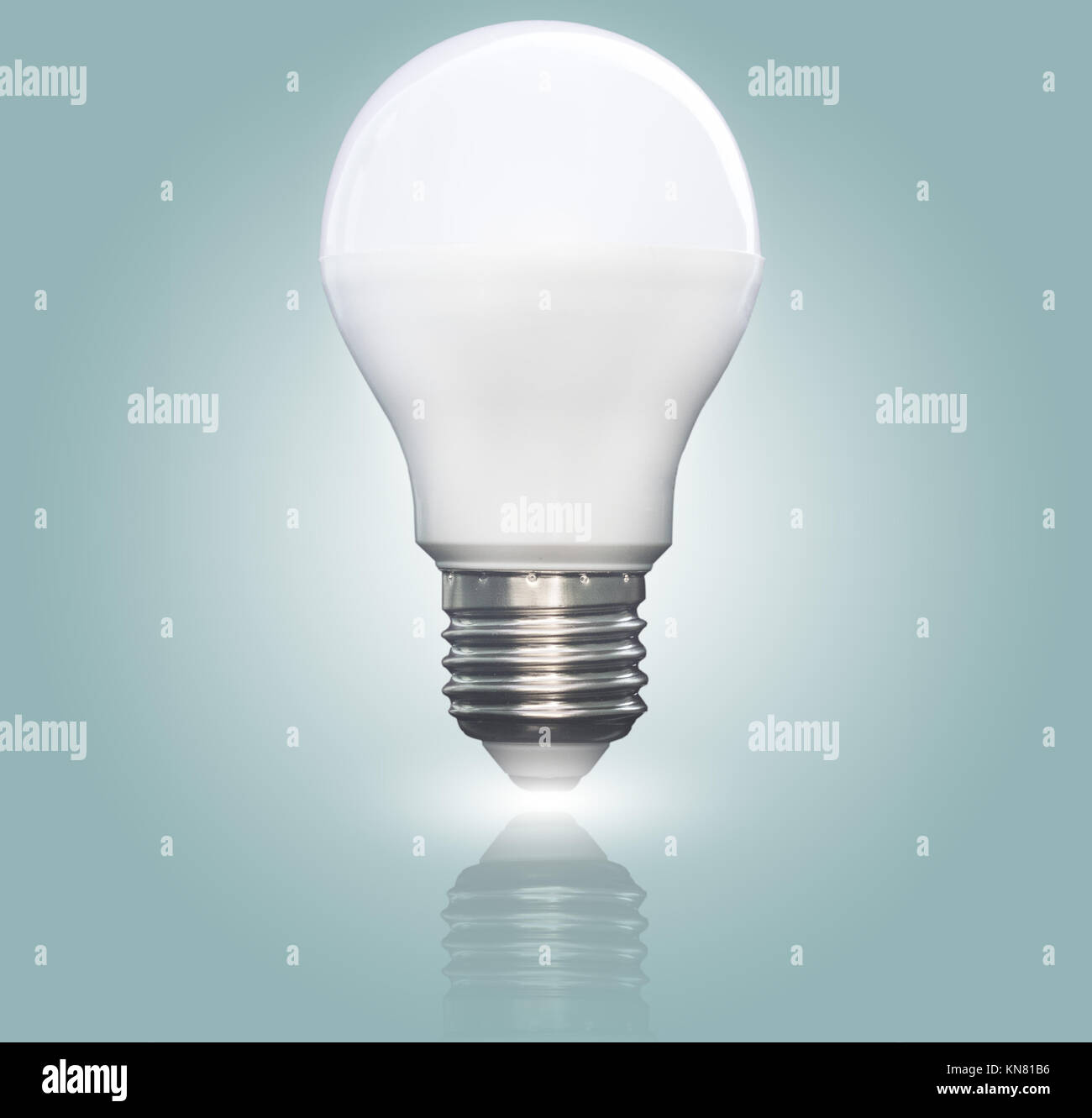 Lit LED light bulb isolated on a blue green gradient background, closeup Stock Photo