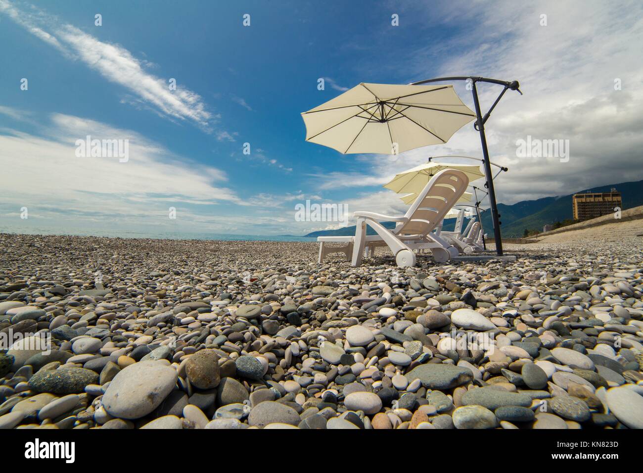 Beach umbrellas and chaise-lounges on the beach, Abkhazia, Black sea Stock Photo