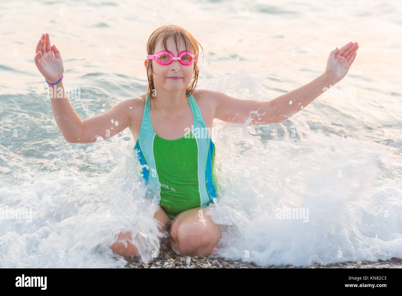 Preteen girl with goggles having fun at sea wave. Stock Photo