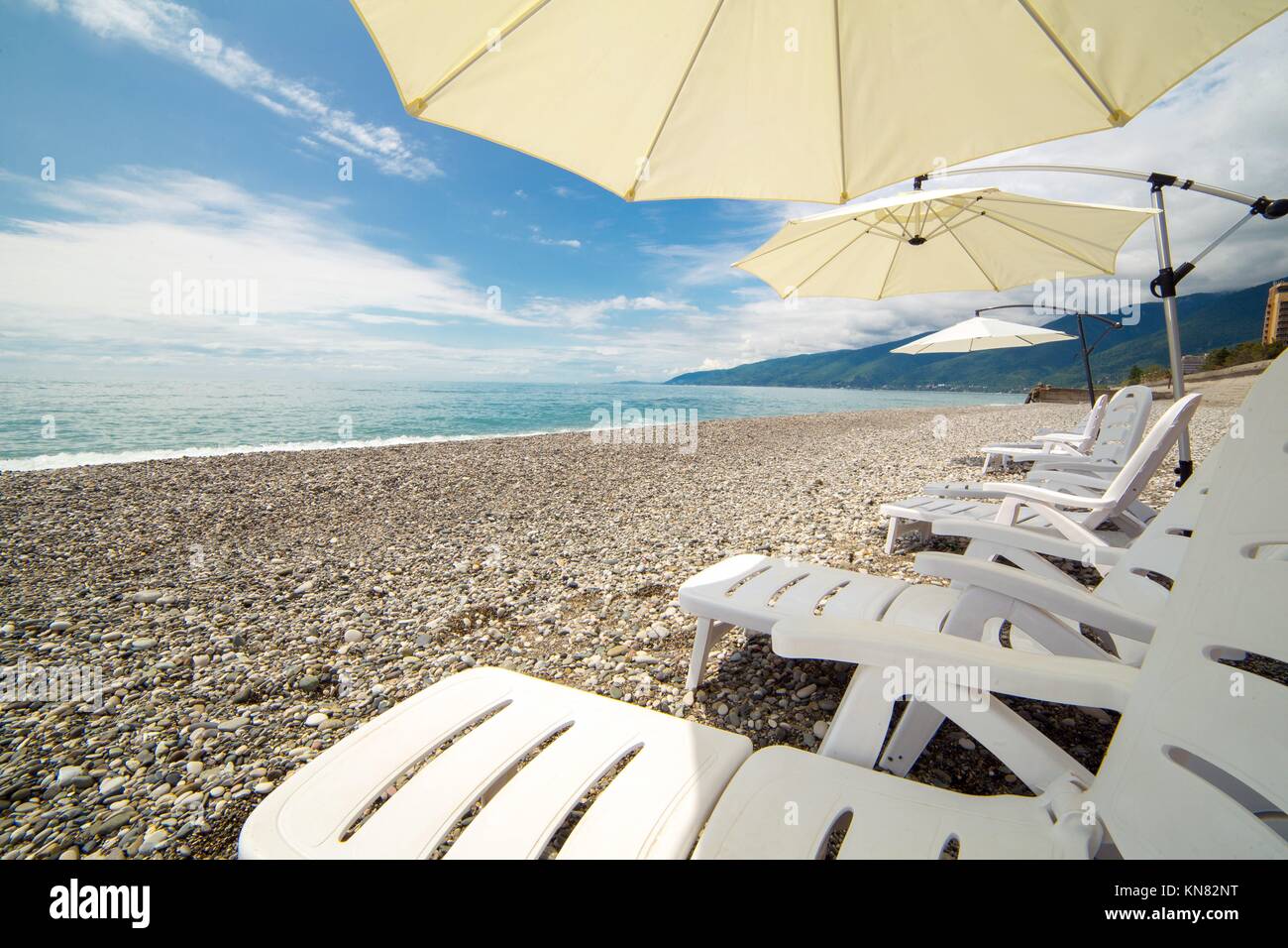 Beach umbrellas and chaise-lounges on the beach, Abkhazia, Black sea Stock Photo
