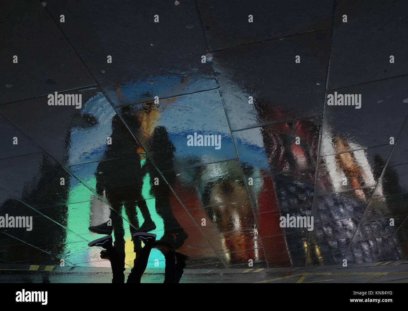 London, UK. 10 December, 2017. Snow predictably turned to rain in Piccadilly Circus, central London leaving shoppers and tourists to wander among the reflections of Piccadilly Circus’s new electronic billboards. The billboards were installed in October 2017 and react to external factors such as the weather. Roland Phillips/Alamy Live News. Stock Photo
