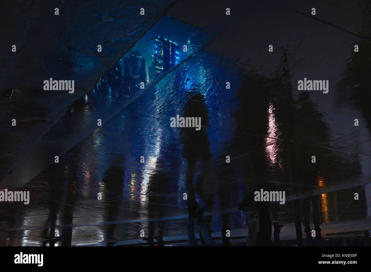 A cityscape from the Piccadilly Circus advertising screens is reflected on a pavement in London Stock Photo