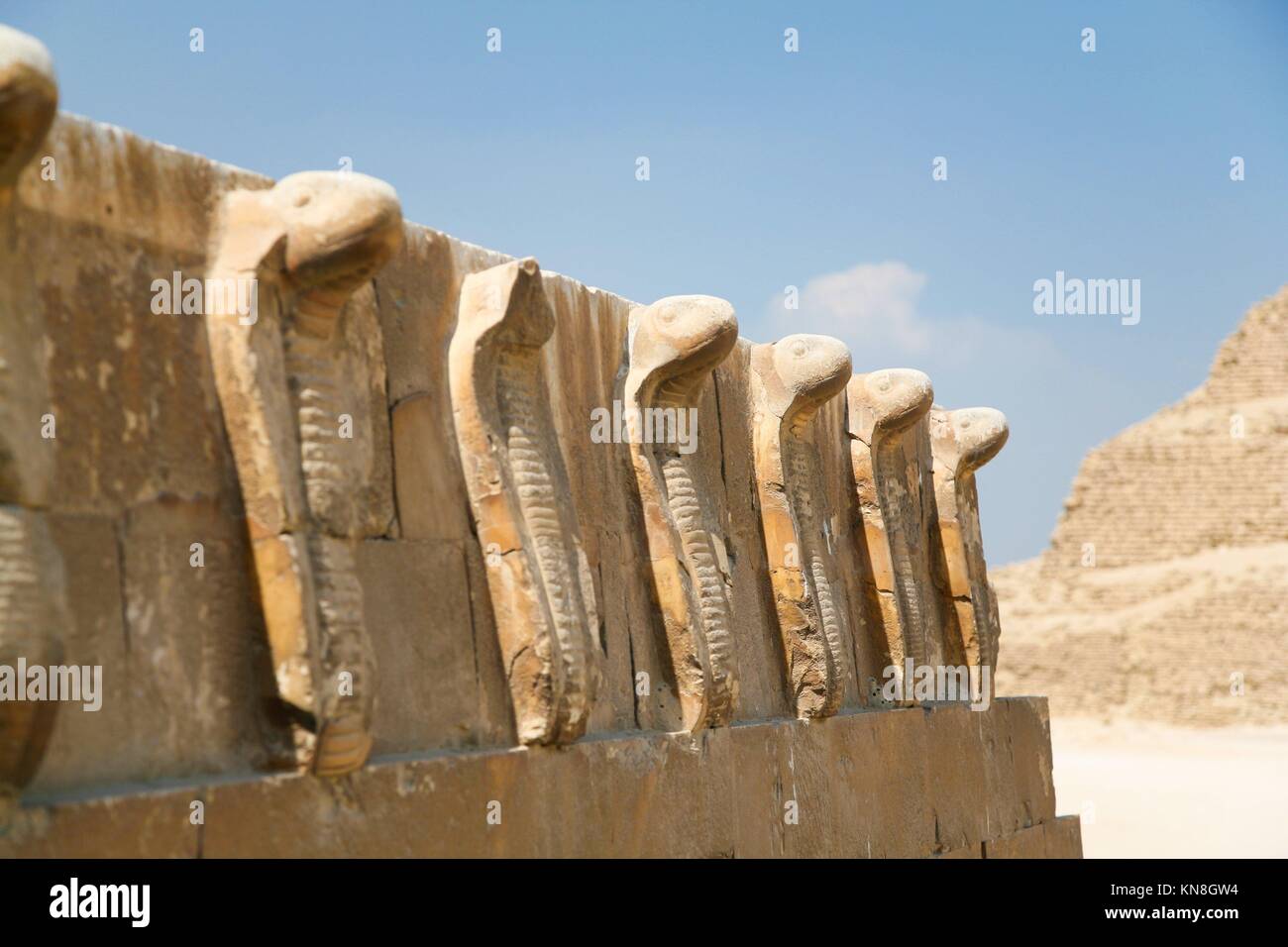 egyptian wall engraved with sculptures of cobra snakes next to Stock