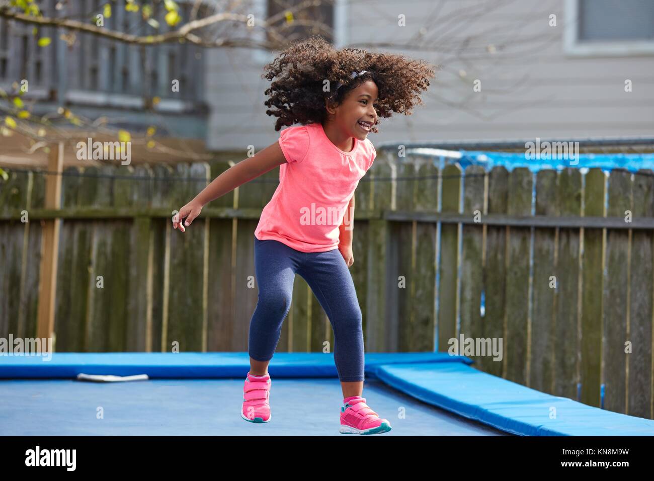 Kid toddler girl jumping on a trampoline playground in the backyard latin ethnicity. Stock Photo