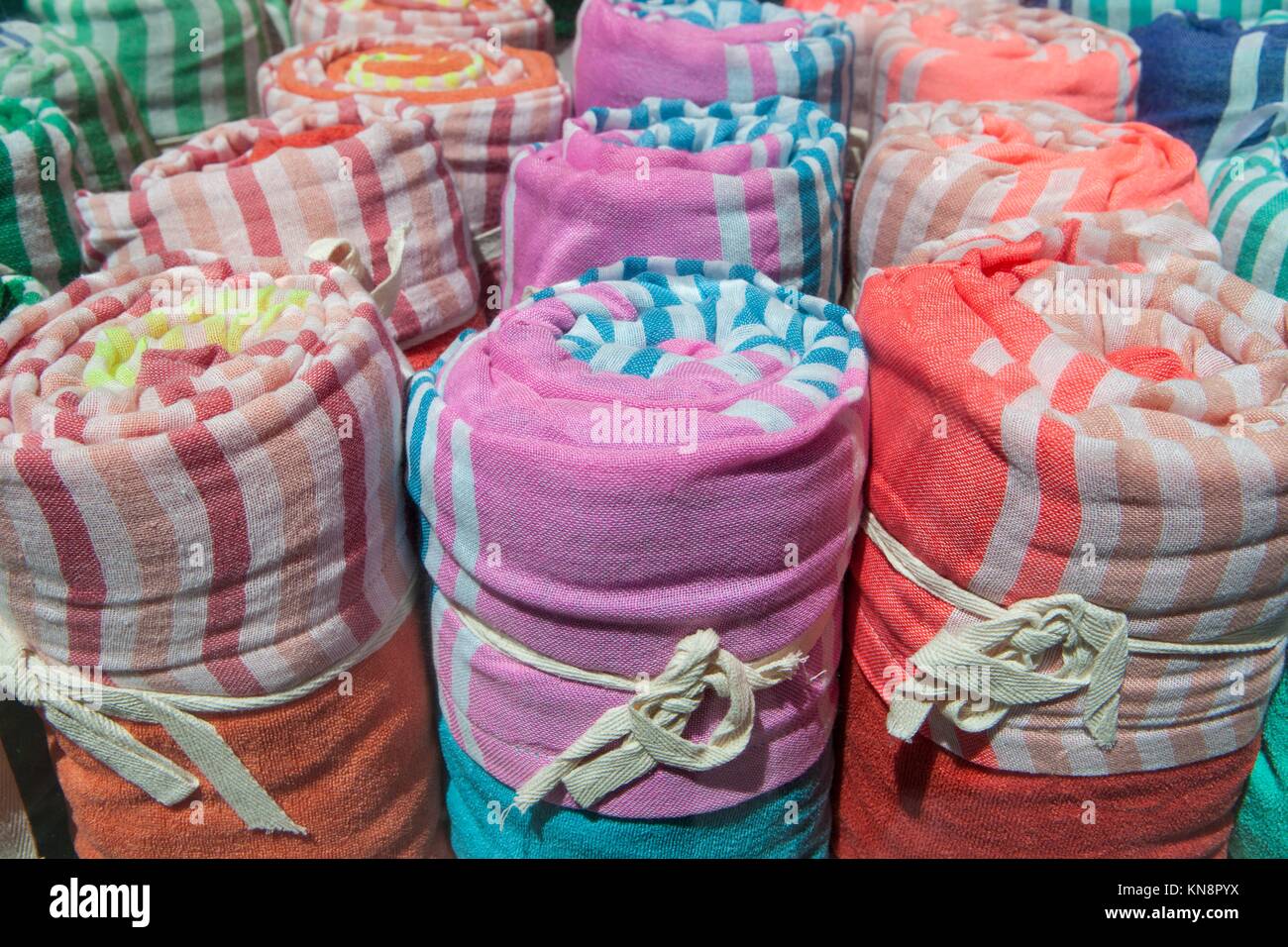 Loads of many rolled colorful light cotton blankets. Closeup. Stock Photo
