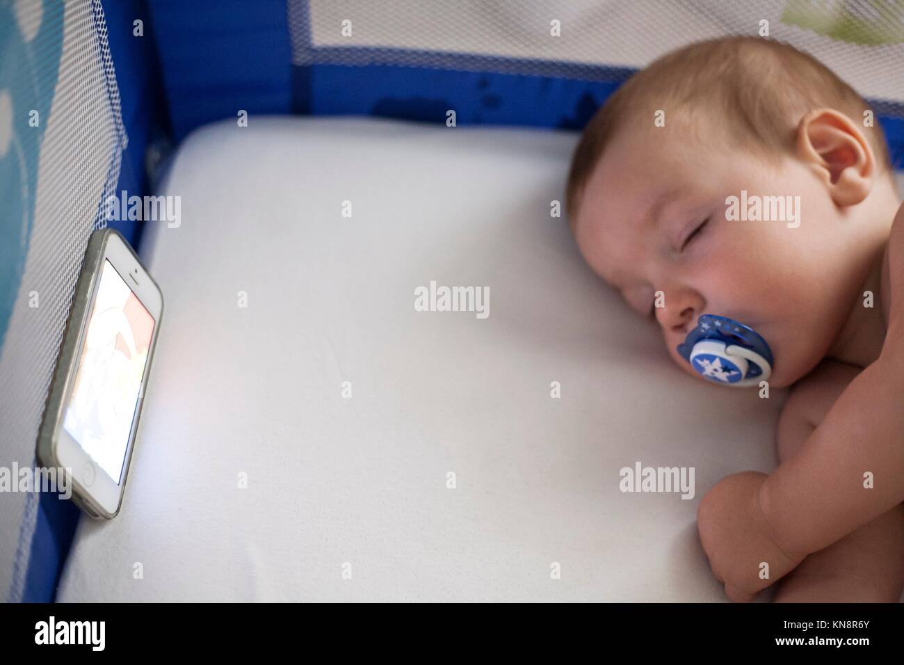 12 month old baby sleeping with a lullaby songs from mobile phone on the crib. Stock Photo