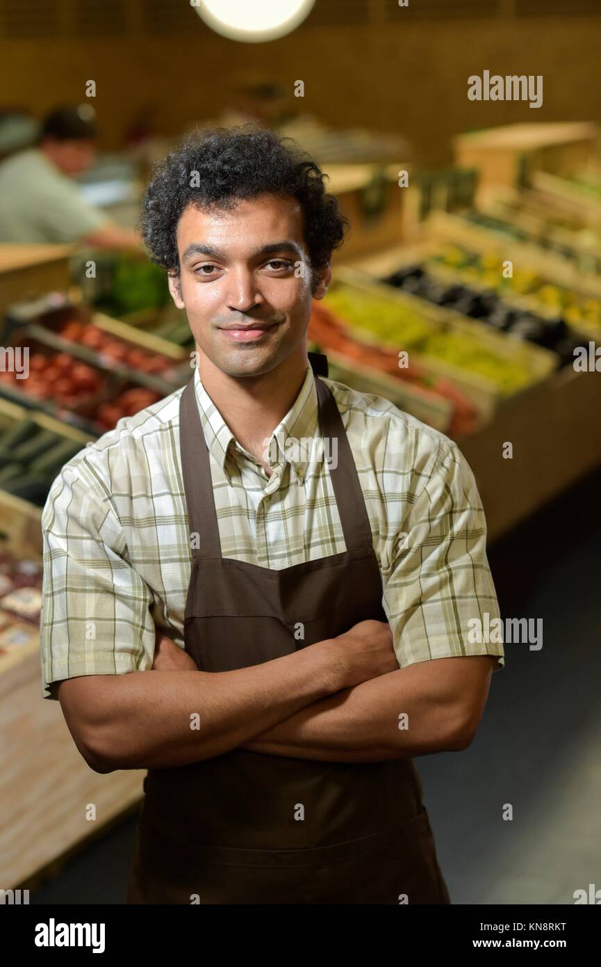 Young Grocery clerk working in produce aisle of grocery store. Stock Photo