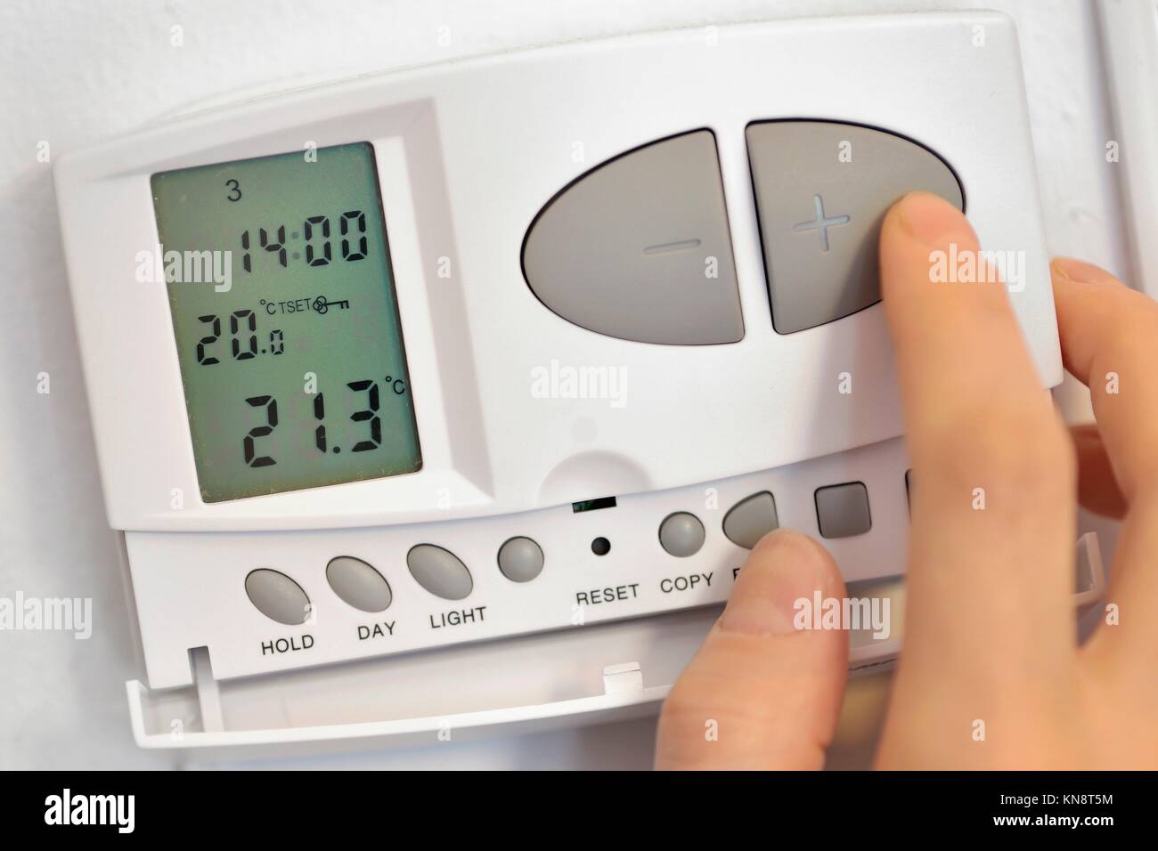 hand pressing button on digital thermostat Stock Photo Alamy
